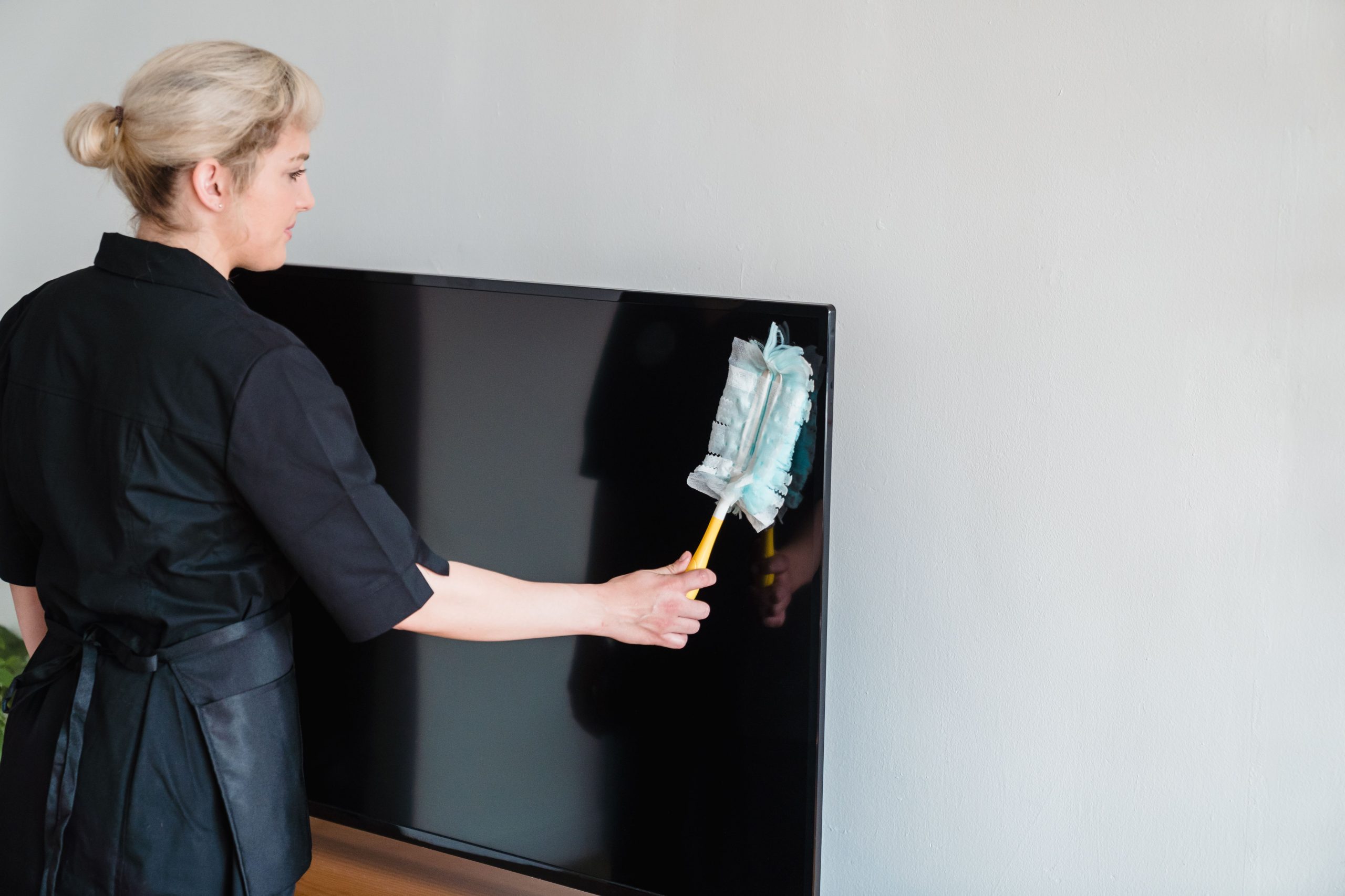 Femme de ménage dépoussiérant un écran de télévision
