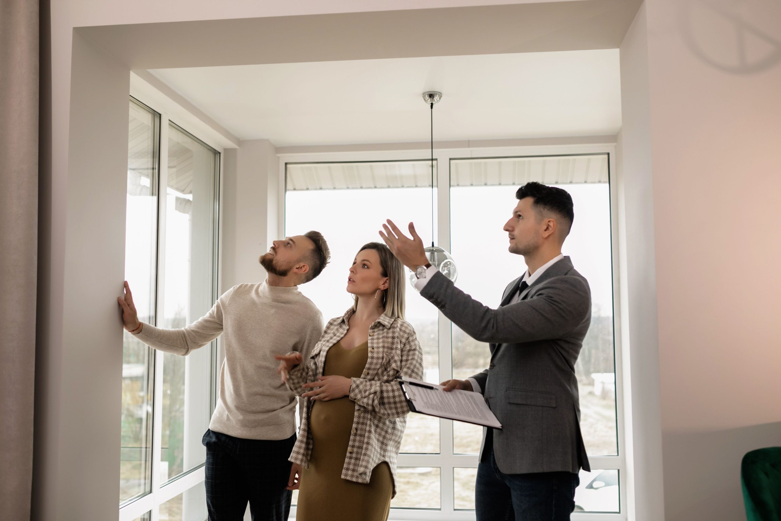 Jeune couple inspectant un appartement moderne avec agent immobilier