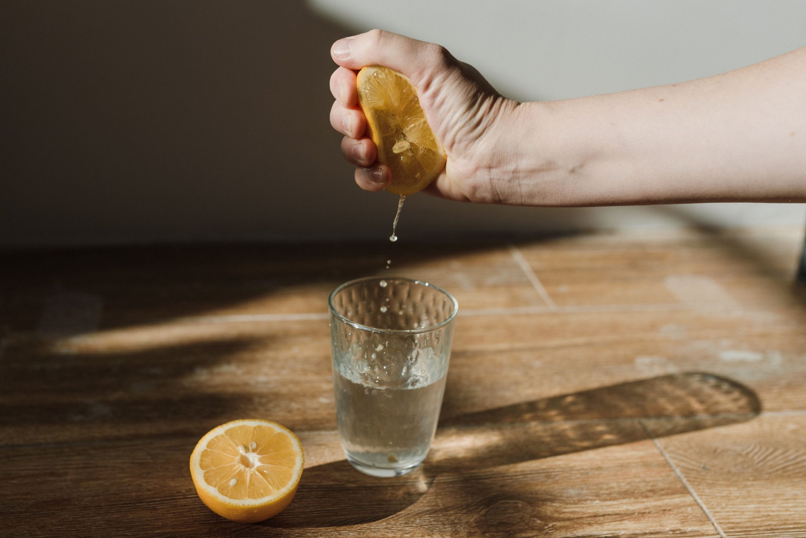 Main pressant un citron frais dans un verre