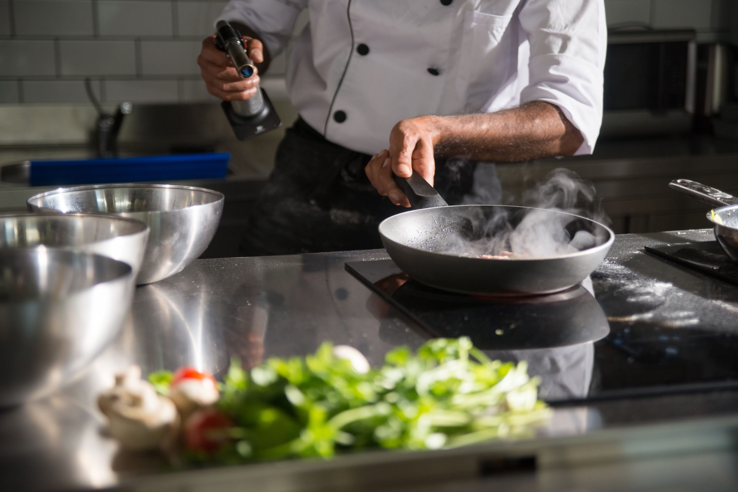 Chef cuisinant avec une poêle sur plaque induction