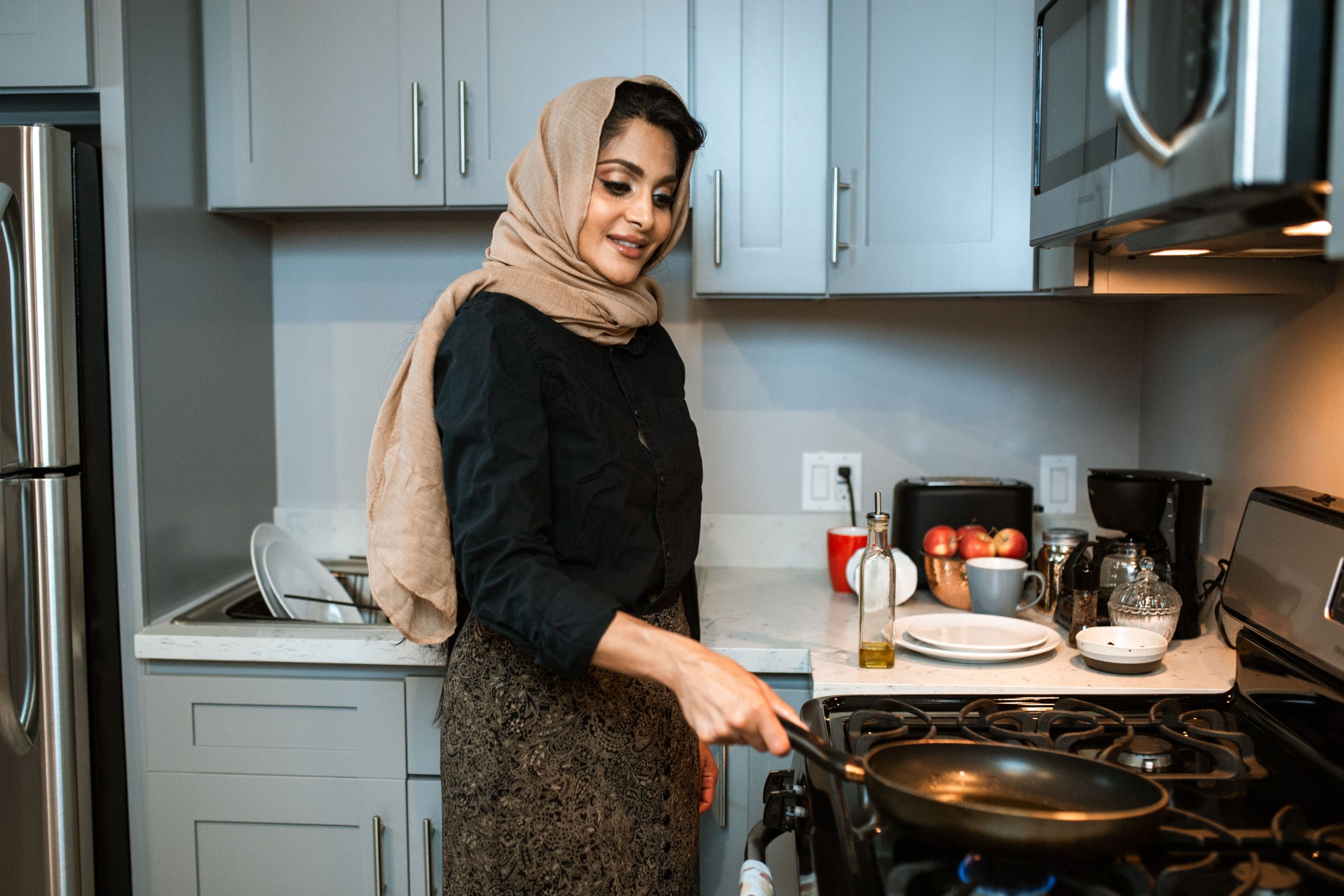 Femme posant une poêle sur une cuisinière à gaz