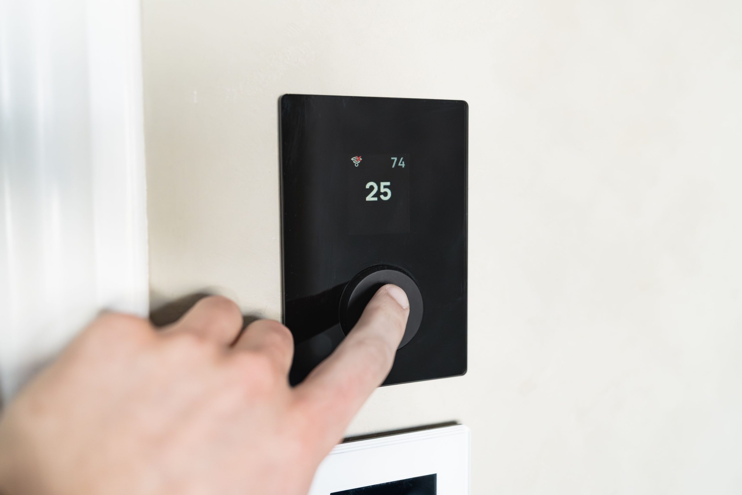 Main réglant thermostat connecté moderne mur
